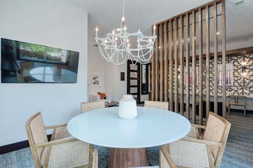 A white table with chairs and a chandelier in a room.