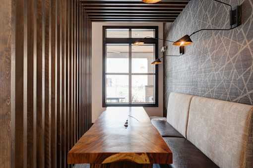 A long wooden table with a couch and a window in the background.