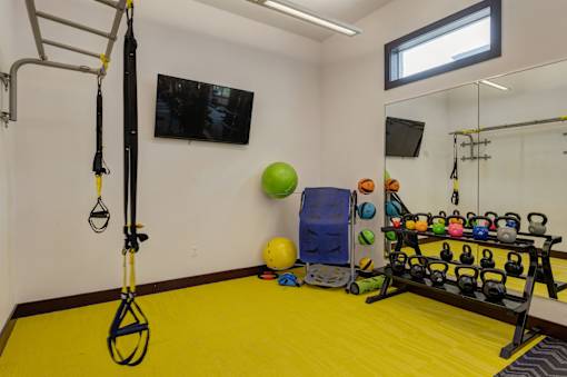 A gym room with a yellow floor and a variety of exercise equipment.