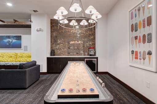 A room with a shiny wooden table and a couch.