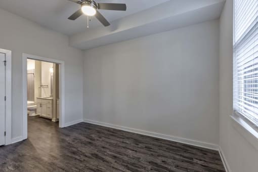 an empty living room with a ceiling fan and a door to a bathroom