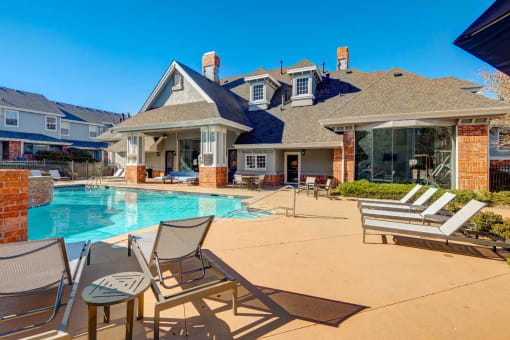a swimming pool with chairs and a house in the background