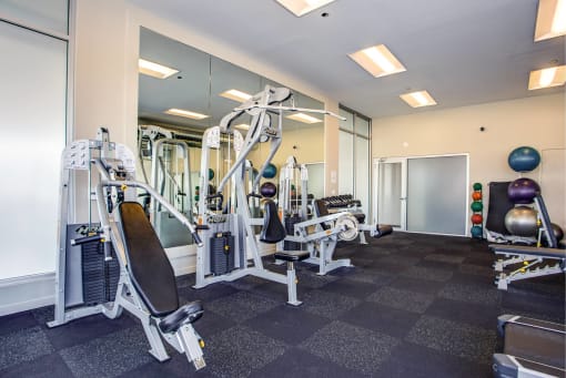 a gym with cardio equipment and mirrors in a building