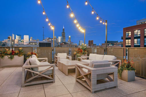 a rooftop terrace with chairs and tables and a city skyline in the background