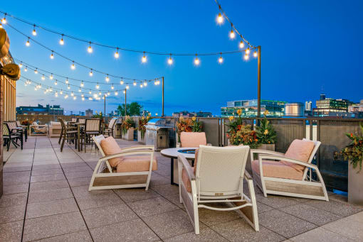 a roof top patio with chairs and tables and lights