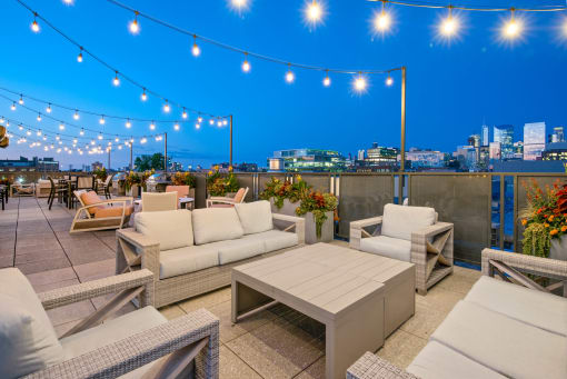 a rooftop terrace with couches and tables and a city skyline