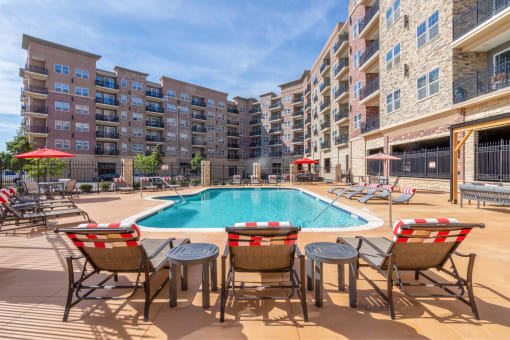 a swimming pool with patio furniture in front of an apartment building