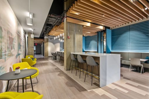 a communal area with yellow chairs and tables and a bar with blue and white walls
