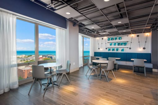a room with tables and chairs and a view of the ocean