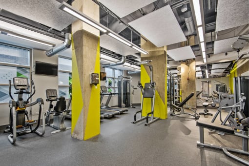 a gym with weights and other exercise equipment in a building with windows
