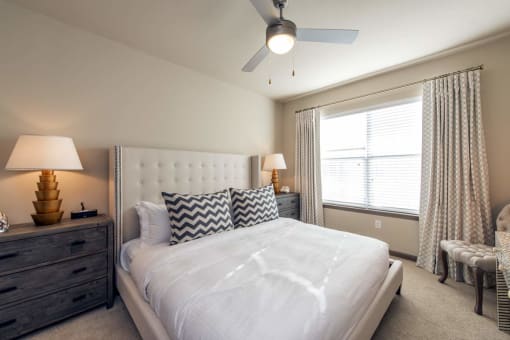 a bedroom with a white bed and a ceiling fan