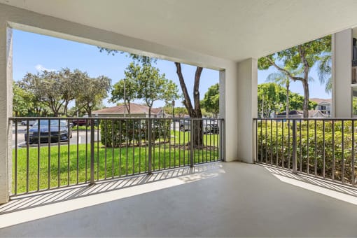 the view of the yard from the balcony of a house with a metal fence