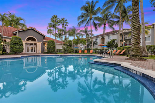 a large swimming pool with palm trees and buildings in the background