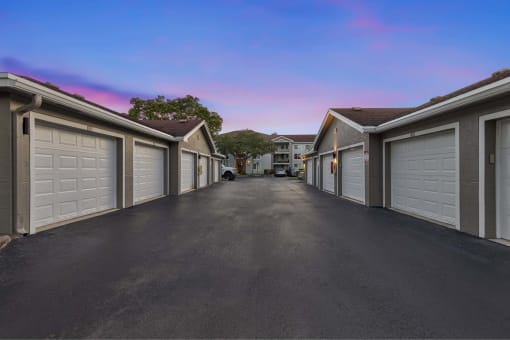 a long driveway with white garage doors at the end of it