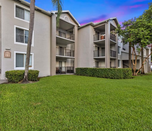 an apartment building with green grass and trees