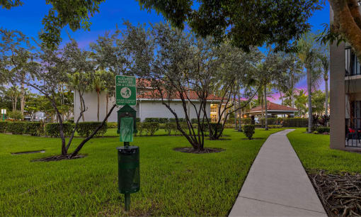 a green parking meter in the grass in front of a building