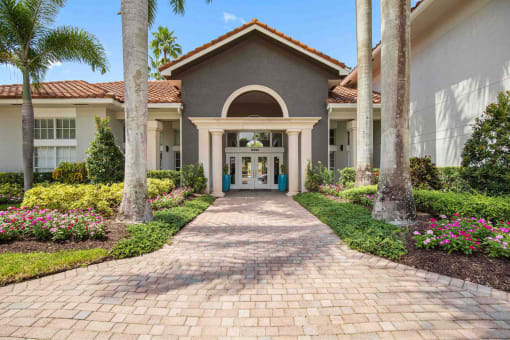 a villa with a walkway and palm trees