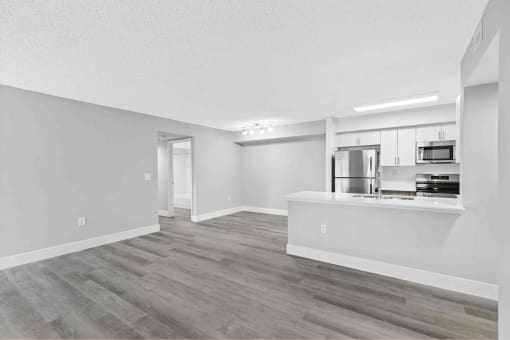 an empty living room and kitchen with a counter top refrigerator and