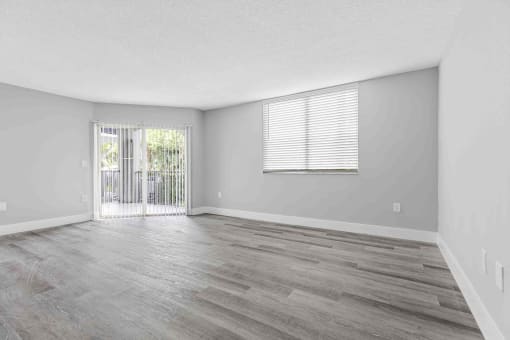 an empty living room with a sliding glass door to a balcony