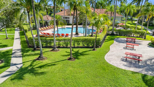 Outdoor view of large resort-style swimming pool with lounge chairs along deck. Covered poolside lounge area near pool. Direct access to clubhouse, which faces pool