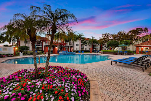 a swimming pool with pink and purple flowers around it