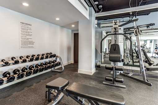 A gym with a bench, weights, and a wall-mounted sign.