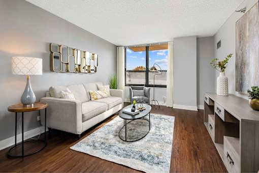 A living room with a grey couch, a coffee table, and a large window.