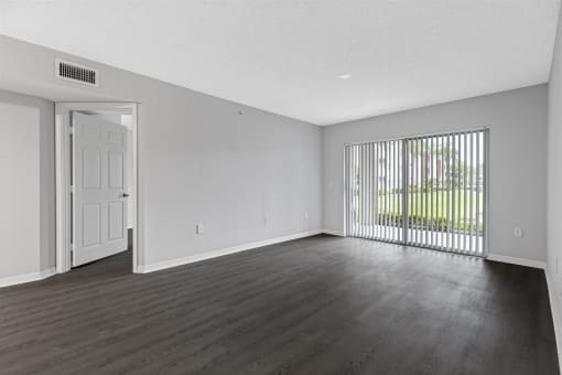 the living room of an apartment with a large window and wood flooring
