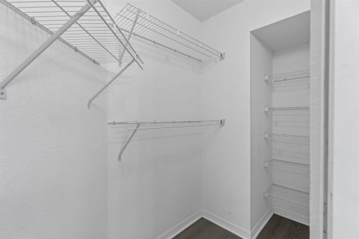 an empty closet in a white room with white walls and metal shelves