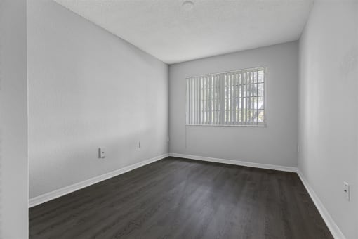 the living room of an empty apartment with wood flooring and a window