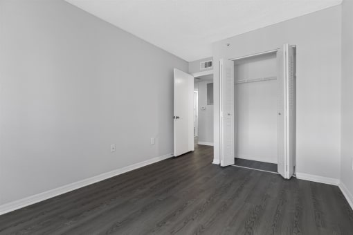 an empty room with white walls and wood flooring and a closet