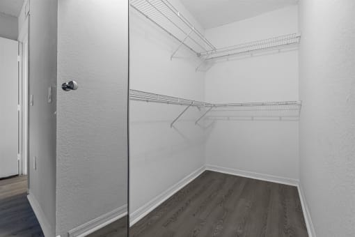 the closet in a bedroom with white walls and wood flooring