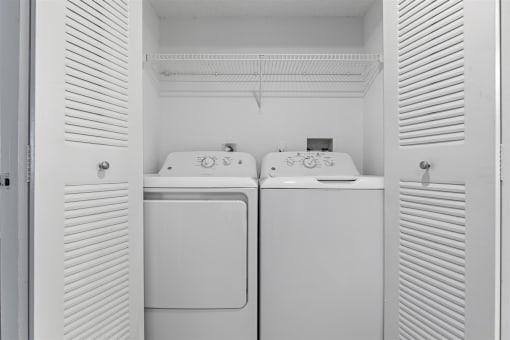 a white laundry room with two washes and a dryer