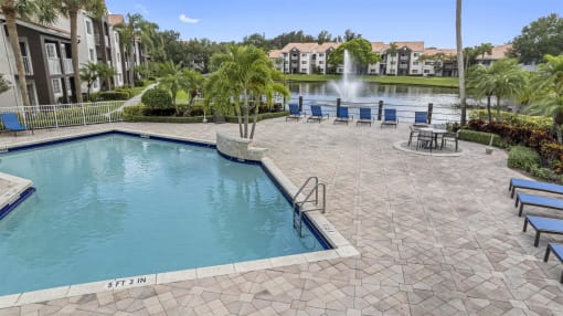 a large swimming pool with a fountain in front of a building