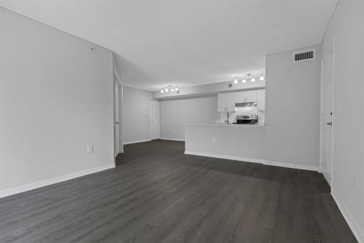an empty living room and kitchen with white walls and wood flooring