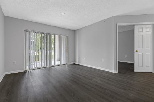 an empty living room with wood floors and a sliding glass door