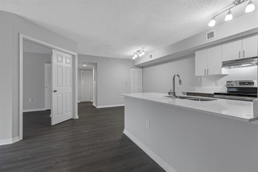 an empty kitchen and living room with white cabinets and a white counter top