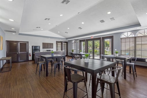 a community room with tables and chairs and a kitchen