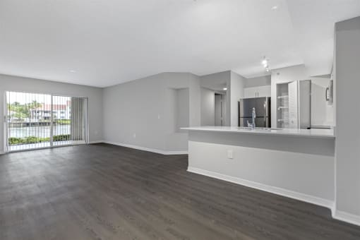 the living room and kitchen of an empty apartment with wood flooring