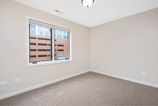 A room with a window and a carpeted floor.