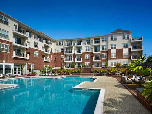 A large apartment complex with a swimming pool in the foreground.