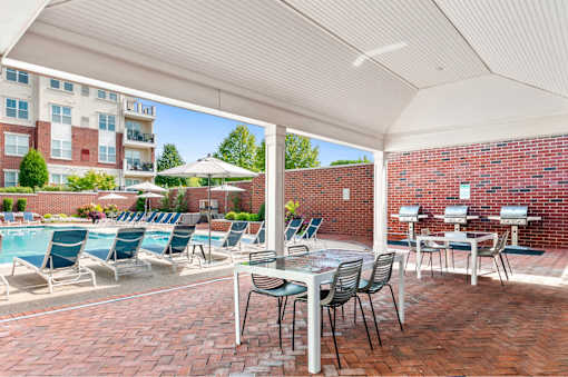 A patio with a table and chairs overlooking a pool.