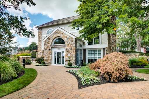 A house with a stone arched doorway and a brick pathway leading to it.