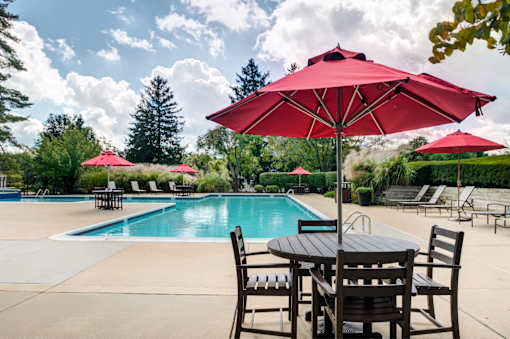 A pool with a table and chairs and umbrellas.
