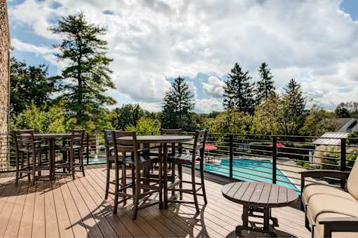 A wooden deck with a table and chairs overlooking a pool.