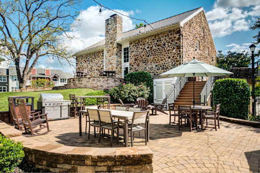 A stone building with a patio and chairs in front.