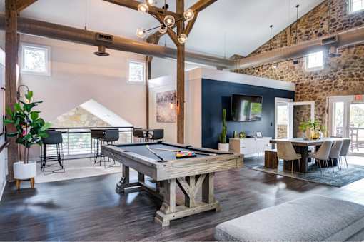 A pool table is in the middle of a room with a blue wall and a TV.