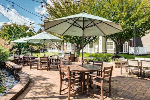 A patio with tables and chairs under umbrellas.