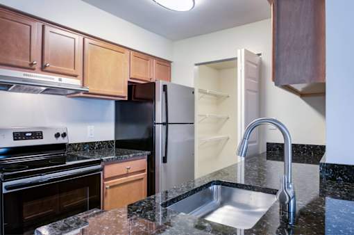 A kitchen with a black refrigerator and a sink.