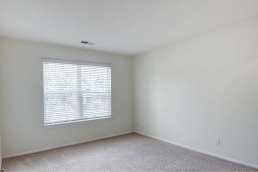A room with a window and carpeted floor.